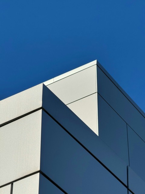 an airplane flying over a building with a blue sky in the background