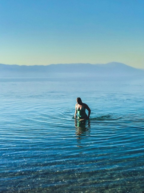 a person standing in the water with a surfboard jXn3