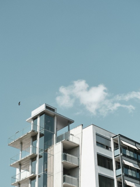 a tall white building with balconies on top of it