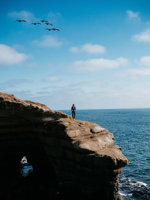 person standing on mountain near ocean during daytime