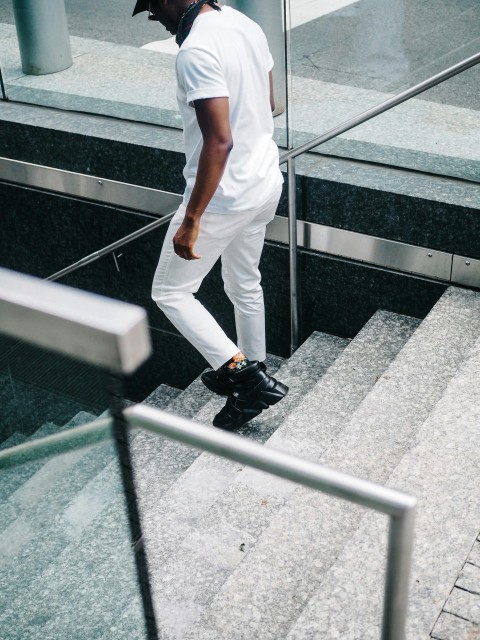 man in white pants and black shoes walking on gray concrete pavement