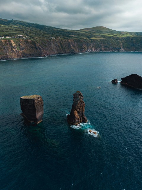 a group of rocks in a body of water with hills in the background