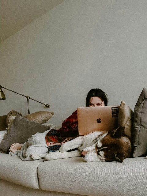 a woman sitting on a couch using a laptop computer