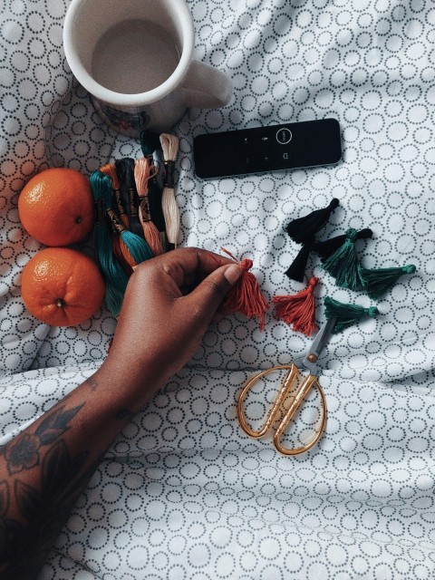 a persons hand holding a pair of scissors next to oranges