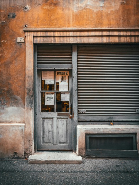 an old building with a closed door and a sign on the door