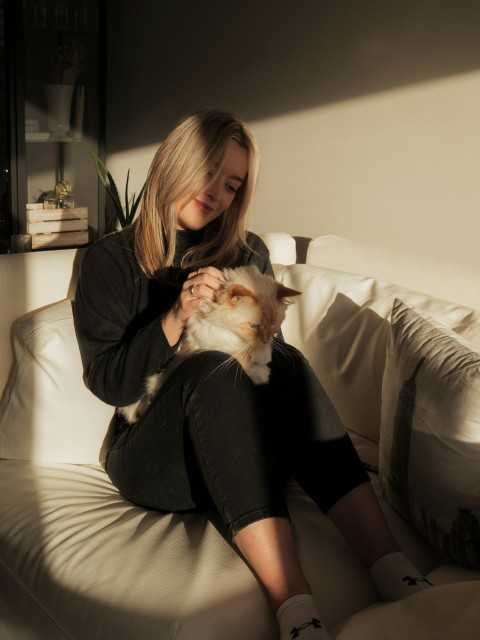 a woman sitting on a couch holding a cat jIH5_