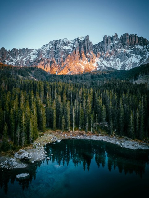 a mountain range with a lake surrounded by trees