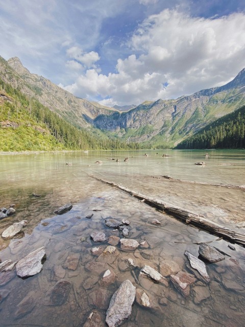 green mountains beside river under white clouds and blue sky during daytime