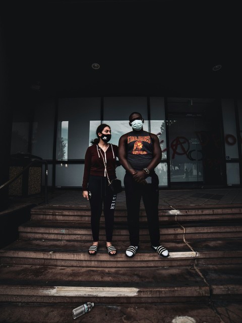 man in black crew neck t shirt and black pants standing on brown wooden staircase