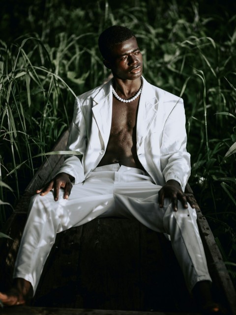 man in white suit sitting on black chair 9UX