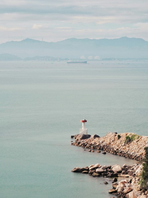 a lighthouse on a rock outcropping in the middle of the ocean