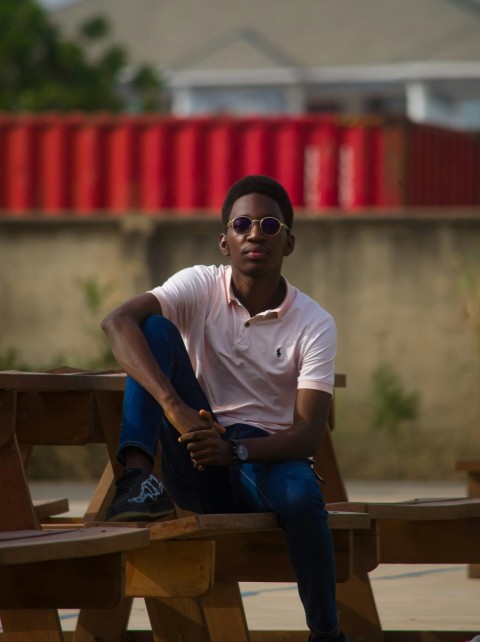 a man sitting on top of a wooden bench