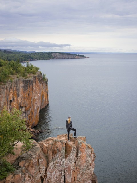 woman standing on cliff near body of water during daytime xm