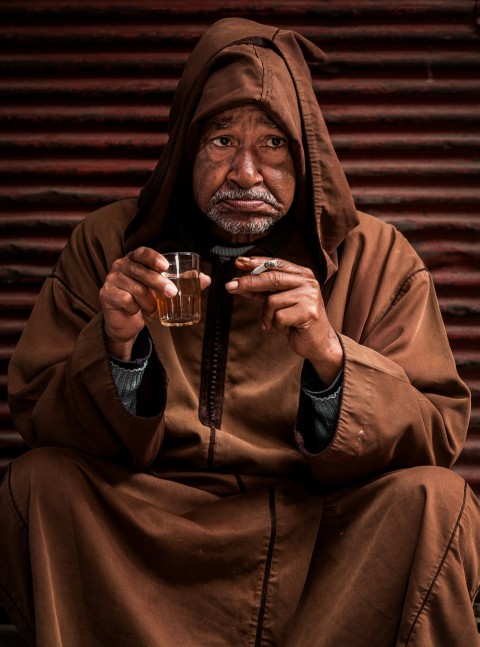 man wearing cloak and holding drinking glass