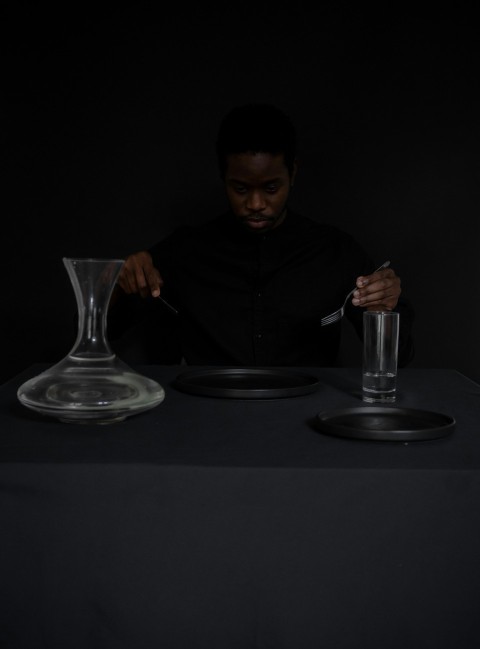 a man sitting at a table with a plate and a glass in front of him