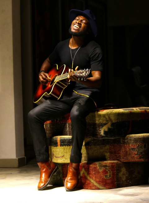 man in black long sleeve shirt and blue denim jeans playing brown acoustic guitar