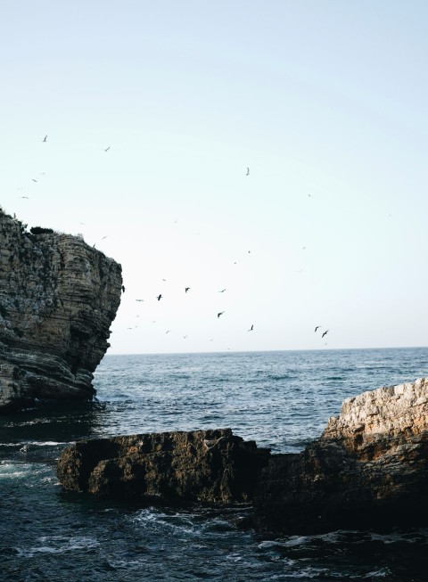 a man standing on top of a cliff next to the ocean