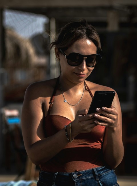 a woman wearing sunglasses and looking at her phone