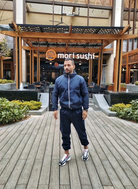 a man standing on a boardwalk in front of a building