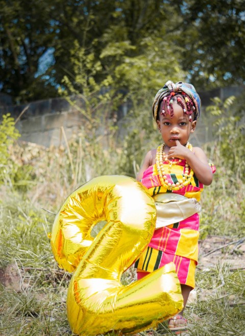 girl in yellow and red dress holding yellow balloon