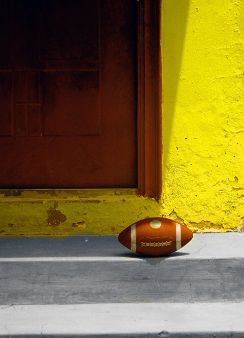 a football laying on the ground in front of a door hwACtTZ7