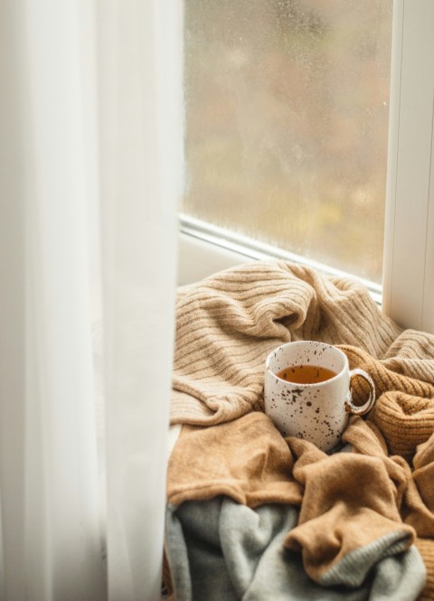 white ceramic mug on brown textile