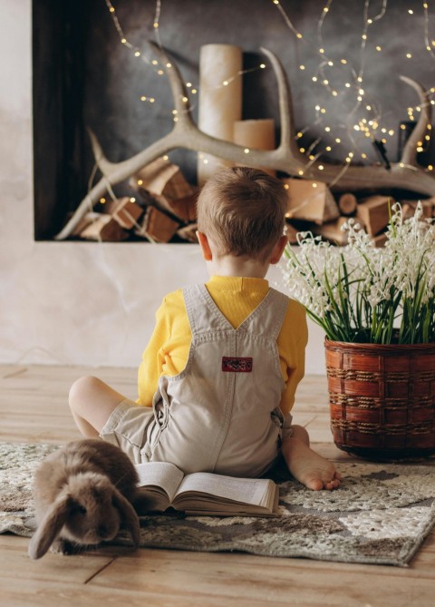 a little boy sitting on the floor reading a book