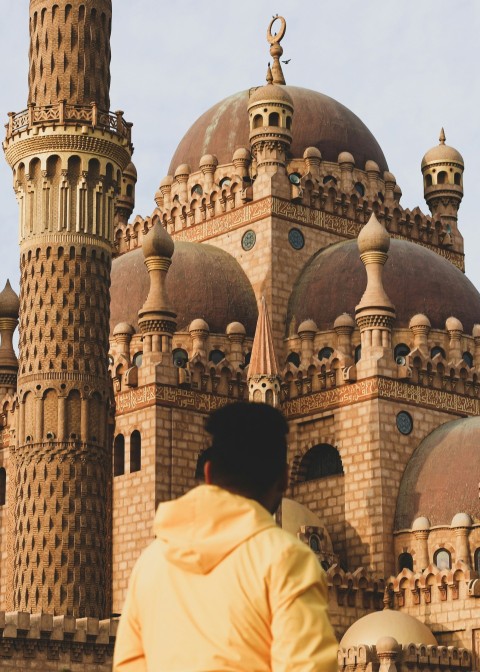 a man standing in front of a large building Wy7K