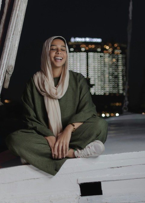 a woman sitting on a ledge in a green outfit