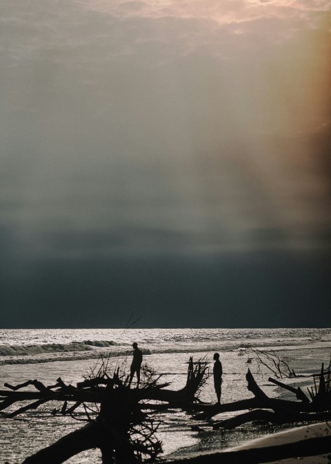 a couple of people standing on top of a beach MQXEXZt