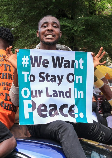 man in orange shirt holding blue and white happy birthday signage