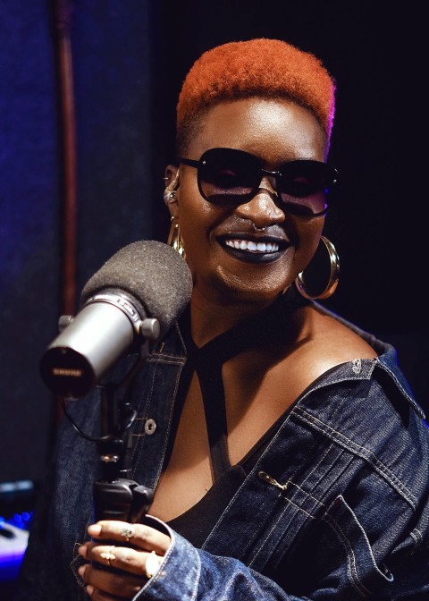 a woman with red hair and sunglasses holding a microphone