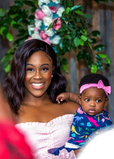 woman in white knit shirt carrying baby in blue and white floral shirt