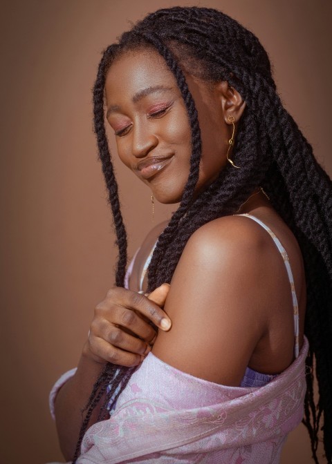 a woman with braids smiling and looking at her cell phone