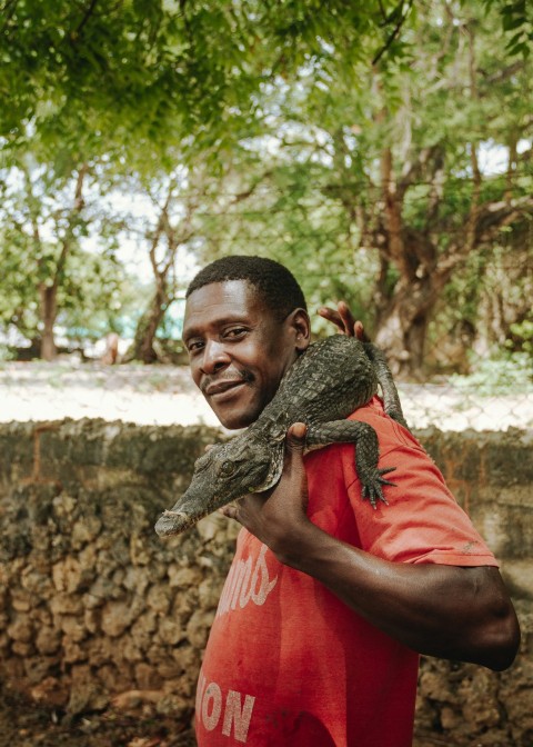 a man holding a small lizard in his hands