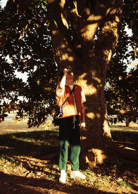 woman in black tank top and black pants standing under tree