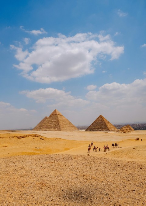 a group of people riding horses in front of three pyramids