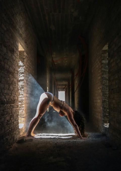 woman leaning forward on ground inside brick hallway O6Qq_T9A