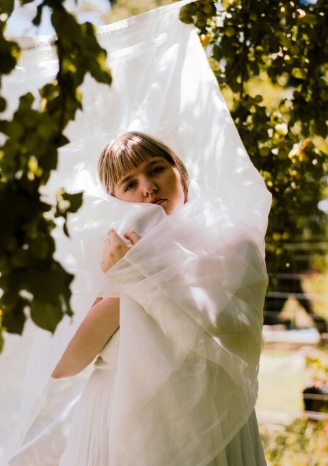 a woman in a white dress standing under a tree