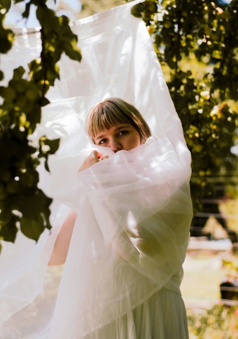 a woman in a white dress standing under a tree