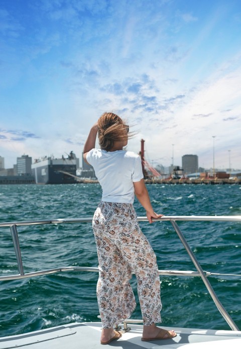 woman in white t shirt and brown floral skirt standing on boat during daytime