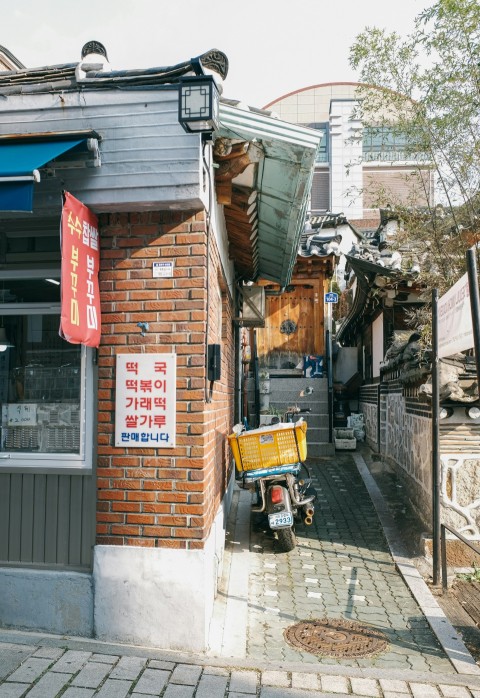 a brick building with a yellow cart parked in front of it N0ZdPHe