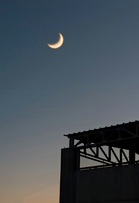 a half moon is seen in the sky above a building