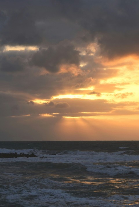 the sun is shining through the clouds over the ocean