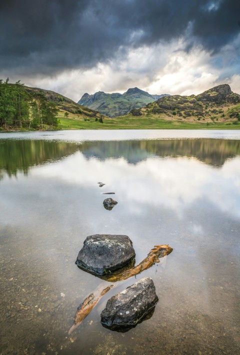 a body of water surrounded by mountains under a cloudy sky