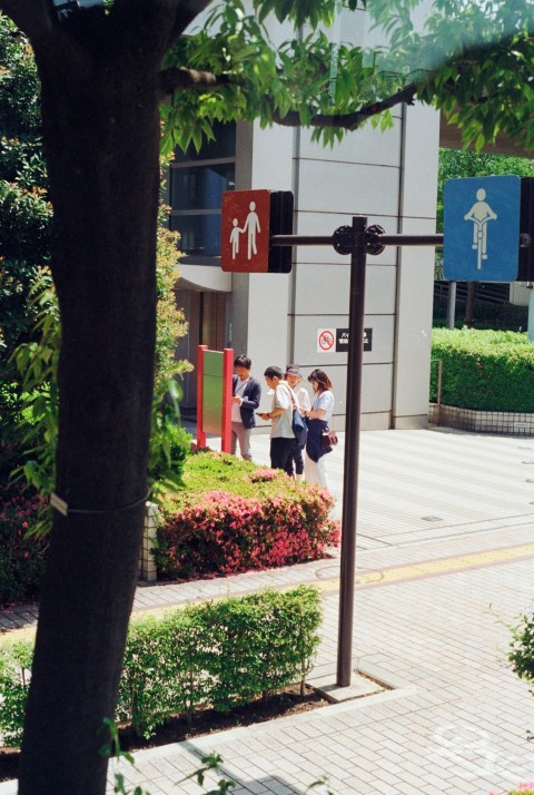 a group of people walking down a sidewalk next to a building