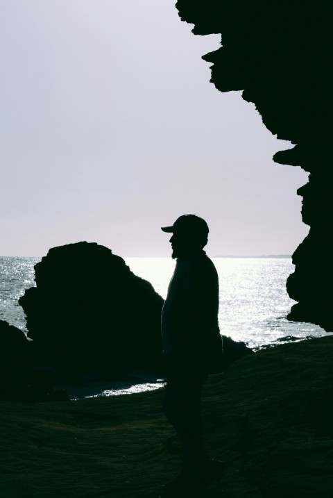 a man standing on top of a beach next to the ocean