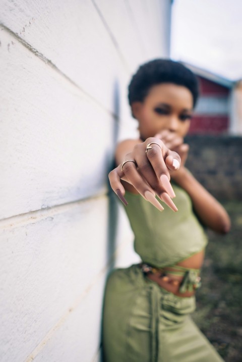 a woman with a ring on her finger leaning against a wall