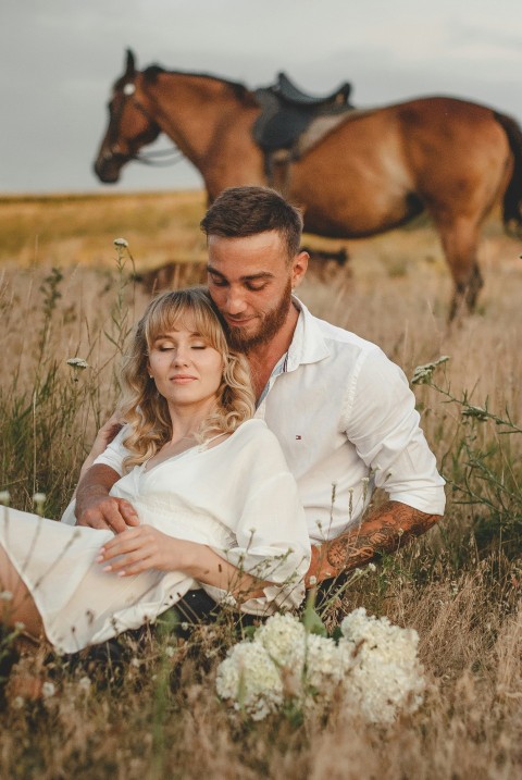 woman in white dress shirt sitting on brown grass field during daytime