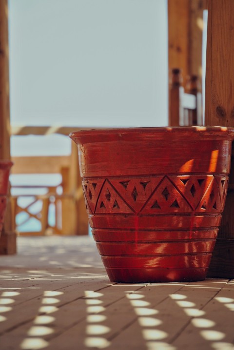 a large red pot sitting on top of a sidewalk